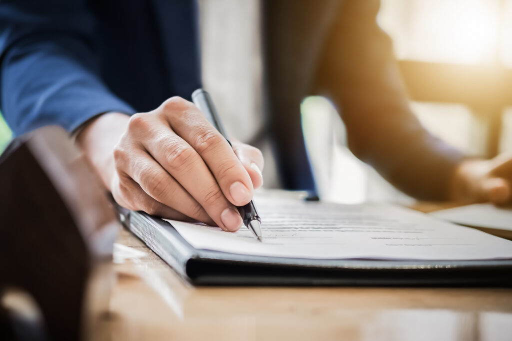 person holding pen signing documents