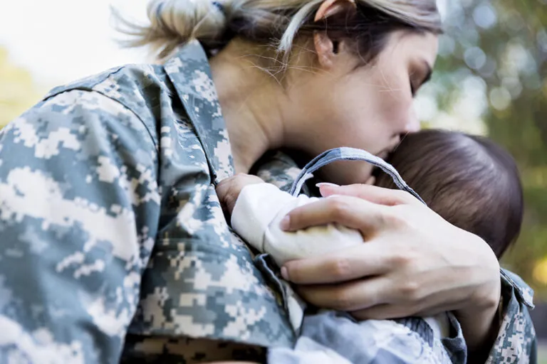 Marine mom holds and kisses her infant child