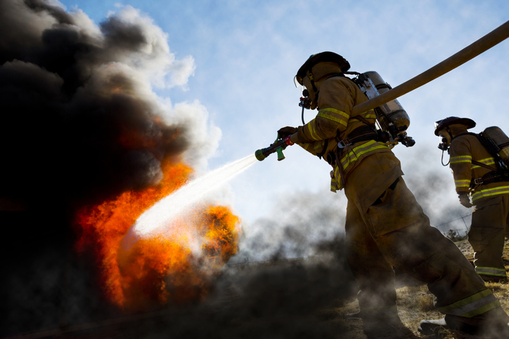 Firefighter in turnout gear extinguishing flames