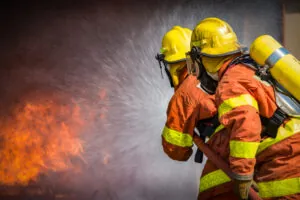 2 firefighters spraying high-pressure water to extinguish fire