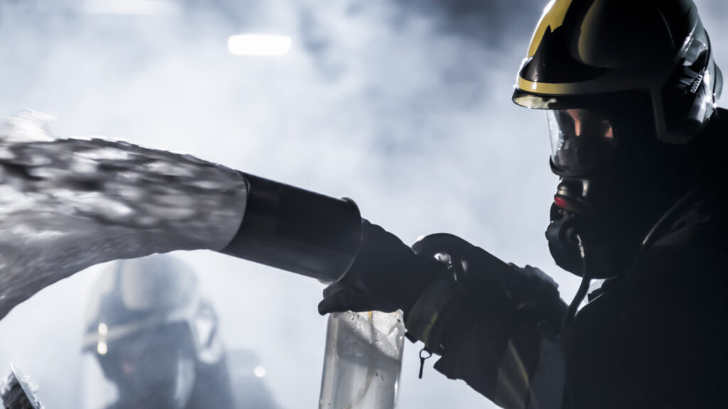 Firefighter in silhouette spraying foam from a hose