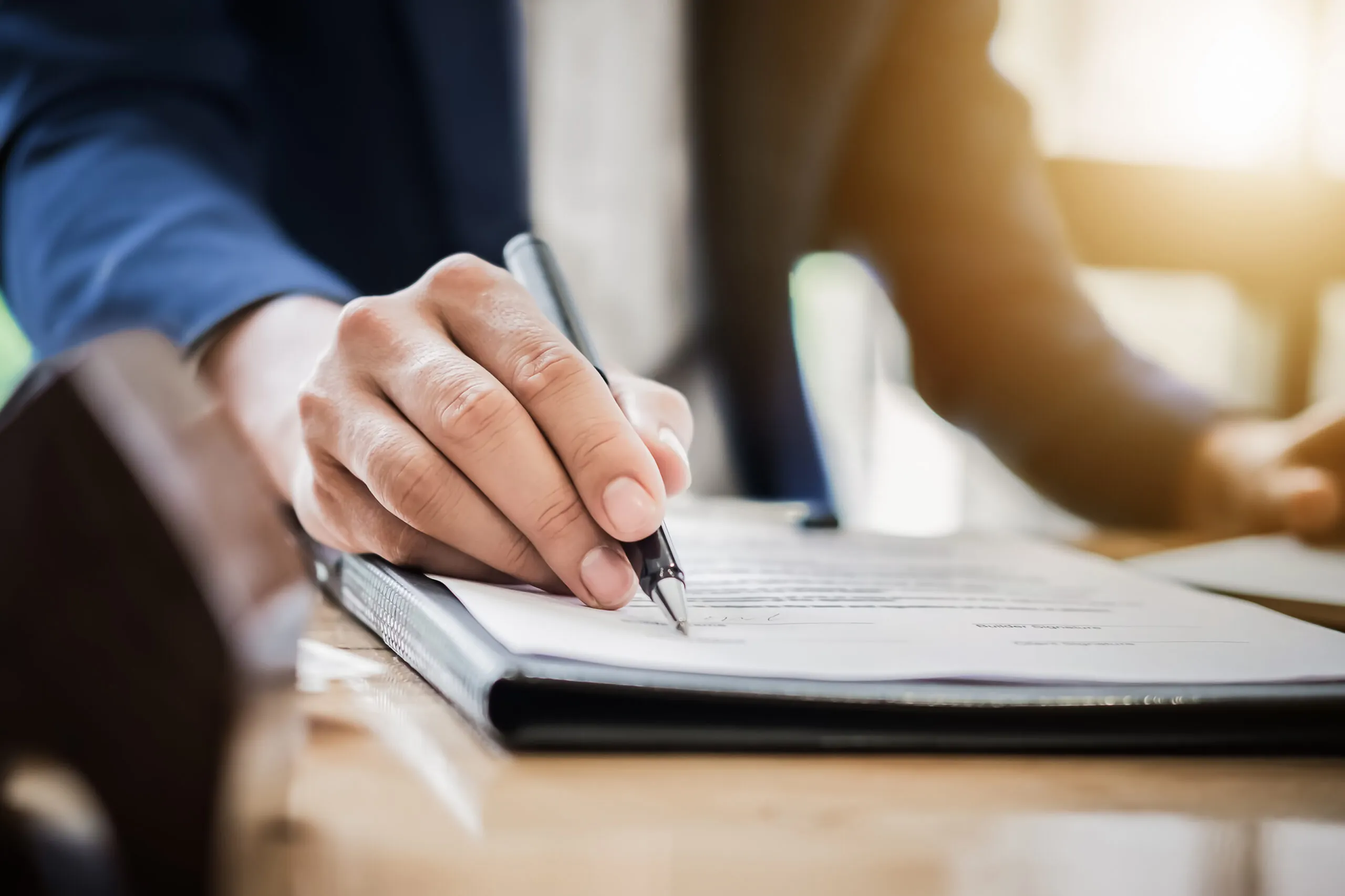 person holding pen signing documents