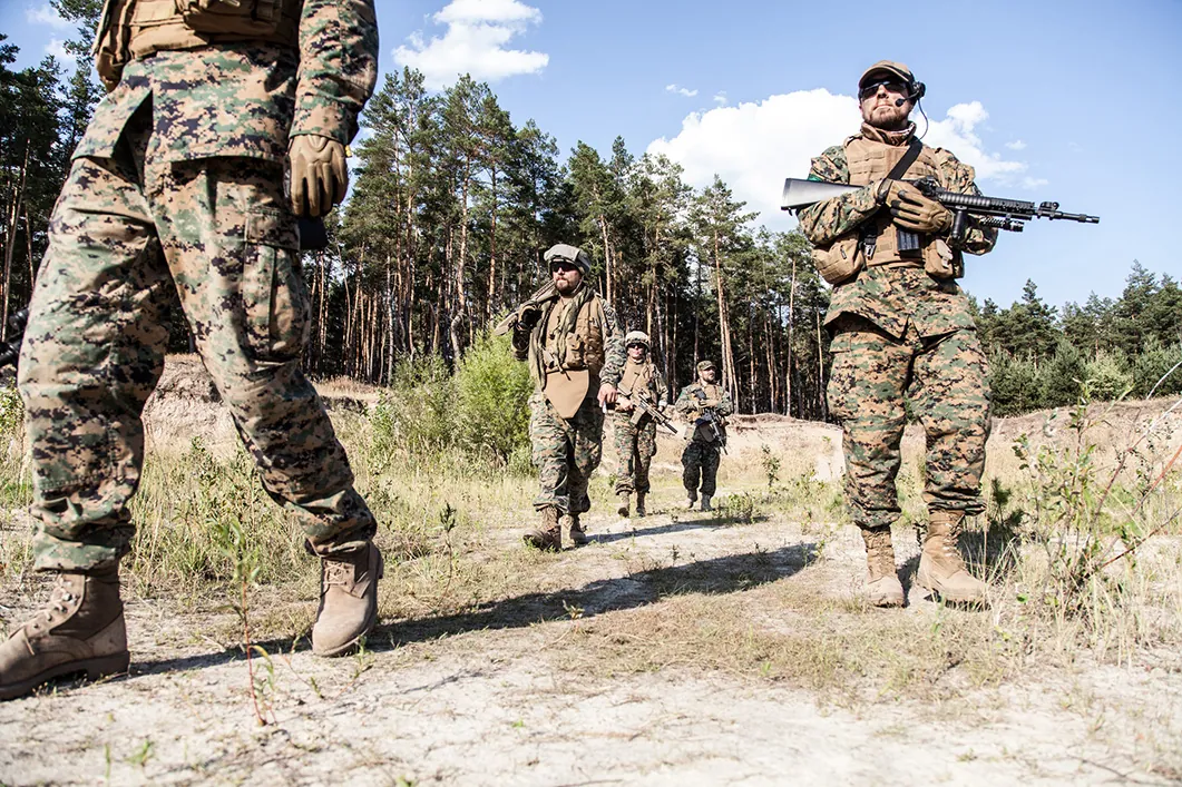 Location shot of United States Marine with rifle weapons in uniforms. Military equipment, army helmet, warpaint, smoked dirty face, tactical gloves. Military action, battlefield