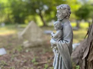 Statue of saint holding an infant in a cemetery