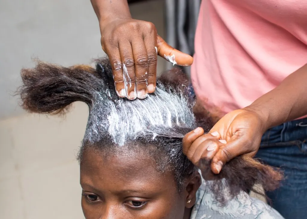 Woman receiving hair relaxer treatment at a salon