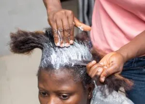 Woman receiving hair relaxer treatment at a salon