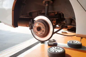 Car on lift with tires removed, showing brakes and brake components