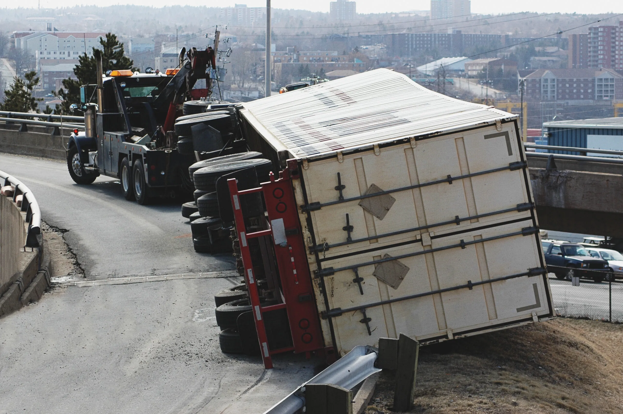 big rig overturned on its side on a curvilinear stretch of road